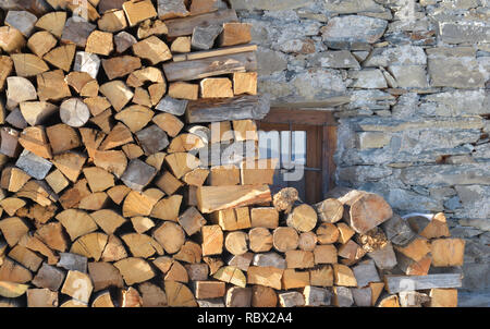 Des tas de bois empilés contre la façade en pierre d'un chalet Banque D'Images