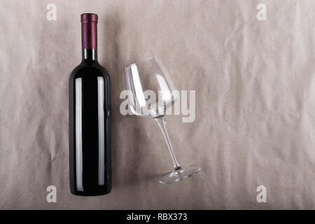 Set de vin - une bouteille de vin rouge avec un verre vide sur un fond gris Banque D'Images