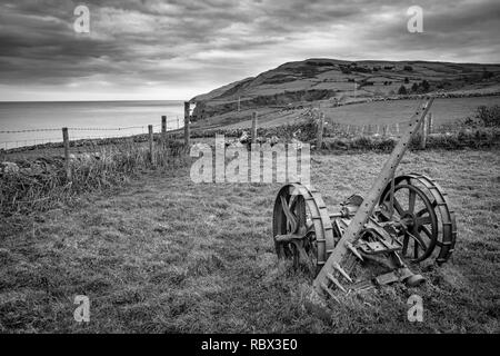 Une pièce vintage de matériel agricole rouillent dans un champ en Irlande. Cette photo a été prise le long de la Côte d'Antrim, en Irlande du Nord. C'est dans un lieu c Banque D'Images