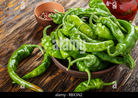 Piment vert placé dans une plaque d'argile sur une table en bois brun. Banque D'Images