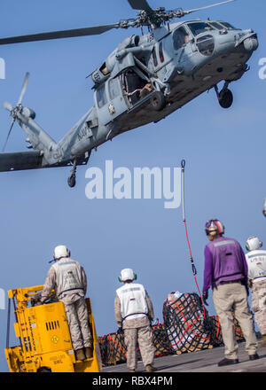 190107-N-PH222-1386 EN MER D'OMAN (jan. 7, 2018) de Marine affecté à la 13e Marine Expeditionary Unit (MEU) et les marins affectés à la San Antonio-classe de transport amphibie USS dock Anchorage (LPD 23) se préparer à récupérer les marchandises livrées à partir d'une Sea Hawk MH-60S Hélicoptère hélicoptère attaché à la lutte contre la mer (HSC) de l'escadron 21, au cours d'un ravitaillement vertical lors d'un déploiement de la Essex Groupe amphibie (ARG) et 13e MEU. L'Essex ARG/13e MEU est souple et persistante Navy-Marine Corps équipe déployée à la 5e flotte américaine zone d'opérations à l'appui des opérations navales à fr Banque D'Images