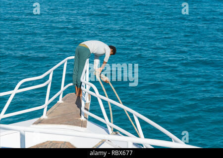 Le mec soulève l'ancre sur le bateau. Banque D'Images