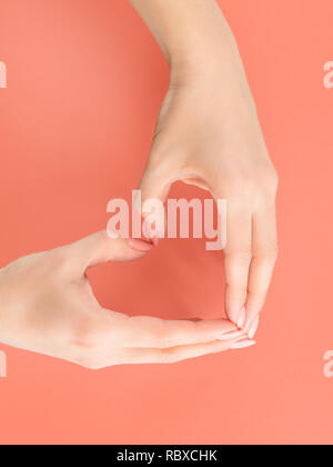 Femme de coeur mains signe. Sur le doux fond rouge Banque D'Images