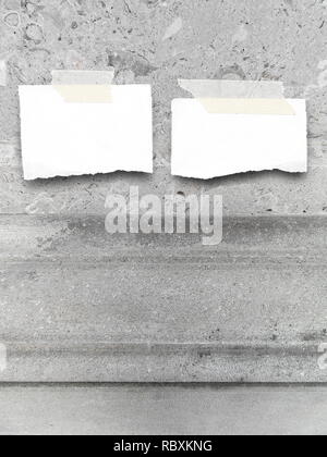 Deux morceaux de papier déchirés en blanc sur fond de mur de pierre en marbre gris Banque D'Images