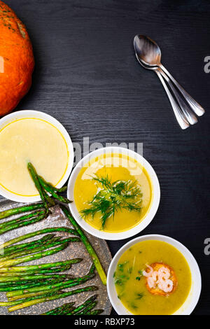 Délicieux potage à la citrouille avec des crevettes, de l'aneth, asperges sur fond de bois sombre, vue du dessus, copy space Banque D'Images