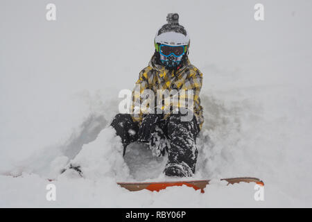 Snowboard garçon est assis en poudreuse sur les pentes des Alpes en France. Banque D'Images