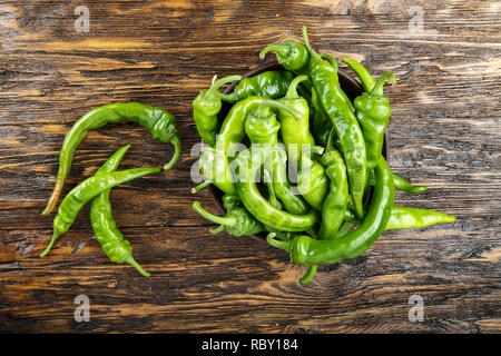 Piment vert placé dans une plaque d'argile sur une table en bois brun. Banque D'Images