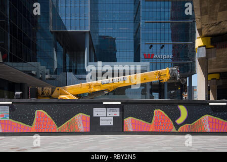 Une grue de construction jaune siège replié derrière un panneau publicitaire coloré en face de l'édifice de la Banque Westpac à Barangaroo sud dans la ville de Sydney. Banque D'Images