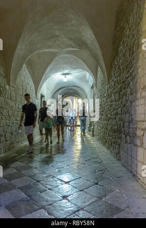 Les touristes de passage par l'étroite rue pierre arches et passage dans la vieille ville historique de Krk, Kvarner, Croatie Banque D'Images