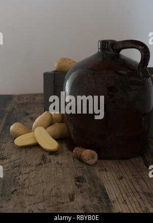 Moonshine vintage sur une table en bois rustique avec des pommes de terre et d'épis de maïs pour la distillation alcool fort de liège Banque D'Images