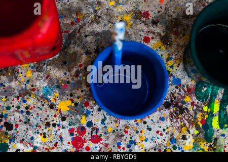 Verres en plastique remplis de peinture sont vu placé sur un trottoir éclaboussé sur le signe de l'atelier de peinture à Cartagena, Colombie. Banque D'Images