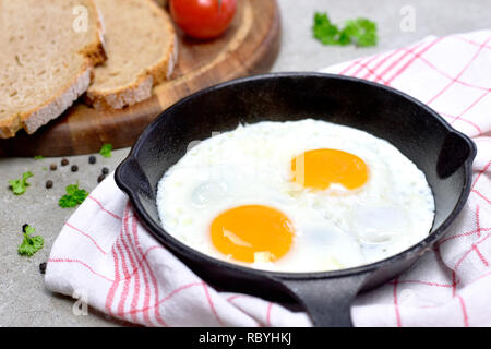 De délicieux œufs frits dans une poêle en fonte. Vue de dessus les oeufs et le pain, petit déjeuner. Banque D'Images