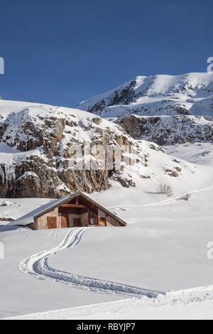 Traces dans la neige menant à la neige cabane dans la station de ski française de l'Alp D'Huez sur journée ensoleillée avec ciel bleu. Banque D'Images