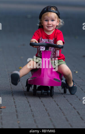 Une photo d'un enfant heureux de la conduite avec un plasma violet voiture comme ride sur toy Banque D'Images