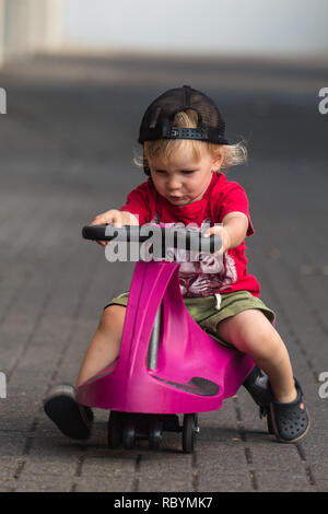 Une photo d'un enfant heureux de la conduite avec un plasma violet voiture comme ride sur toy Banque D'Images