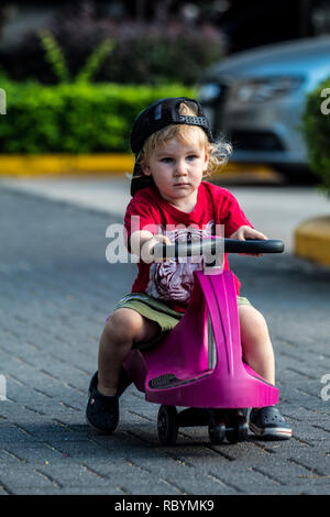 Une photo d'un enfant heureux de la conduite avec un plasma violet voiture comme ride sur toy Banque D'Images