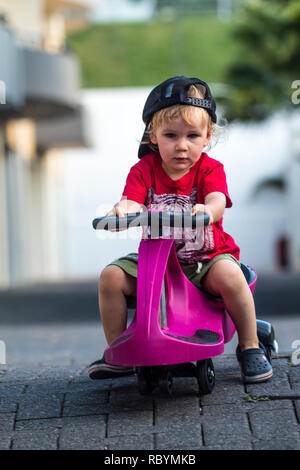 Une photo d'un enfant heureux de la conduite avec un plasma violet voiture comme ride sur toy Banque D'Images