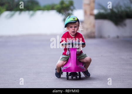 Une photo d'un enfant heureux de la conduite avec un plasma violet voiture comme ride sur toy Banque D'Images