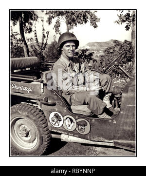 WW2 guerre humour ITALIE Archive avec un GI américain soldat posant dans une jeep militaire en Italie, qui a peint des caricatures amusantes de l'axe de lutte contre le mal - dirigeants de Benito Mussolini, Adolf Hitler et Hideaki Tojo - Le Premier Ministre du Japon. Banque D'Images