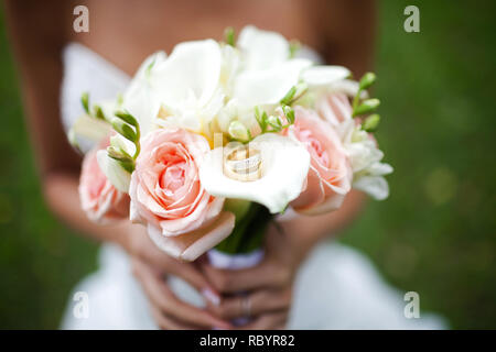 Bouquet de mariage dans les mains d'une méconnaissable mariée. Sur un bouquet d'une couple d'or de mariage. Photo en gros plan. Banque D'Images