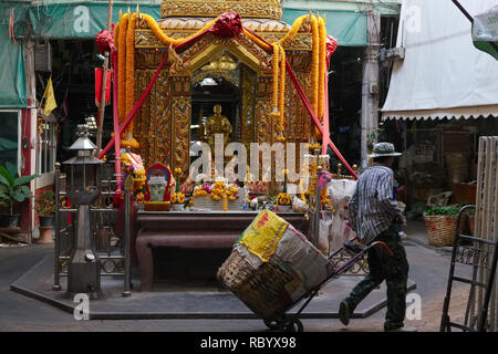 Un portier à Pak Klong Talaat, Bangkok, Thaïlande, de légumes, de fruits et d'un marché aux fleurs, passe un sanctuaire dédié à la gardien spirituel de l'marché Banque D'Images