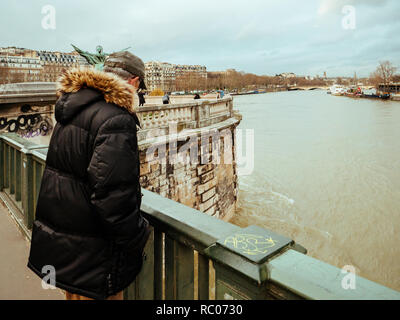 PARIS, FRANCE - Jan 30, 2018 : senior man parisien regarder la Seine près de la Tour Eiffel comme le dépassement de la rivière remblais après des jours de forte pluie Banque D'Images