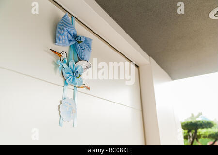 Cigogne bleu traditionnel suspendu à porte avec ruban et Bow, dans l'extérieur de la maison Banque D'Images