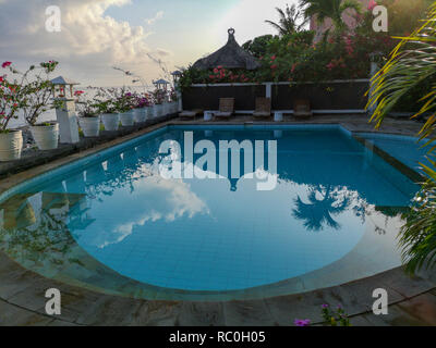 Piscine à l'Kembali Beach Bungalow resort dans le village d'AMED. Les fleurs et le ciel reflète dans la surface de l'eau. Banque D'Images