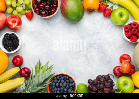 Des fruits sains, frame Framboises Fraises Oranges Pommes Prunes Raisins kiwis mangues bleuets sur le tableau blanc kaki Banque D'Images
