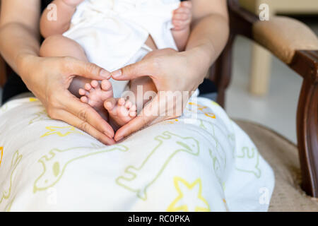 Les pieds de bébé nouveau-né sur les mères de famille, en forme de coeur et d'amour gratuit. Banque D'Images