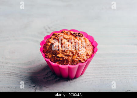 Gruau cuit dans un moule à muffins en silicone rose sur fond de cuisson en bois clair. Banque D'Images