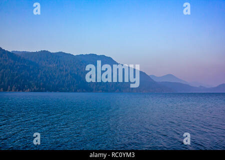 Montagnes derrière sur le lac en été, le soir au coucher du soleil dans l'eau reflète les couleurs Banque D'Images