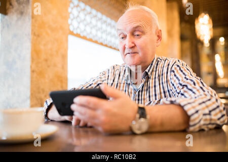 Choqué man using smartphone in cafe Banque D'Images