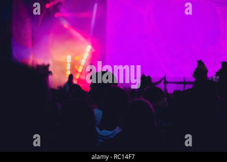 Silhouette d'une grande foule au concert contre un stade bien éclairé. Temps de nuit concert de rock avec des gens s'amusant levée les mains en l'air et acclamer les musiciens Banque D'Images