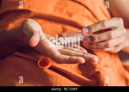 Un médicament dans les mains d'un homme qui est malade et se trouve sur le lit Banque D'Images