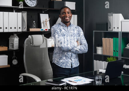 Portrait of young black man in office avec mains jointes sur sa poitrine Banque D'Images