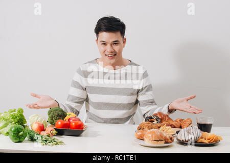 Homme avoir choix difficile entre les aliments sains et malsains Banque D'Images