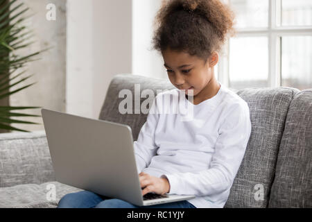 Curieux de l'Afrique de l'âge préscolaire mixed race girl using laptop at home Banque D'Images