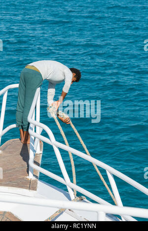 Le mec soulève l'ancre sur le bateau. photo verticale. Banque D'Images