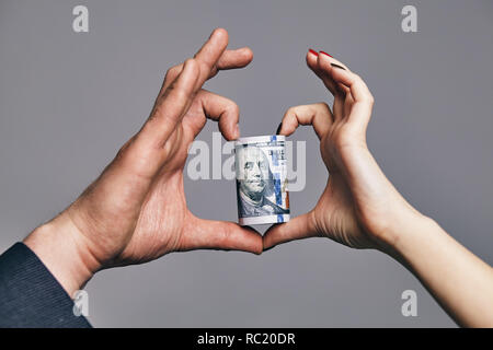 Un rouleau de dollars avec le coeur en deux mains. love money concept Banque D'Images