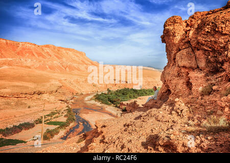 Tazelefte, Maroc - le 9 octobre 2015 : un homme âgé est assis sur une falaise à l'ombre donnant sur la magnifique vallée d'desolating viev de la rivière de l'Ounila. Paysage d'Afrique du Nord incroyable . Vue fascinante de la colline à la vallée au Maroc Banque D'Images