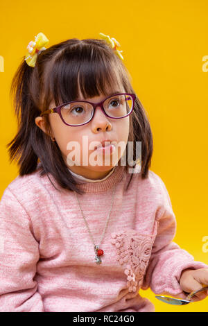 L'écoute petite fille aux yeux bruns ayant le syndrome de Banque D'Images