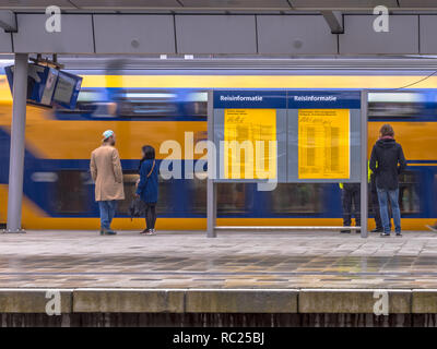 Double-decker train intercity arrivant sur la gare centrale d'Utrecht pendant que les passagers sont en attente sur la plate-forme dans des conditions de pluie Banque D'Images