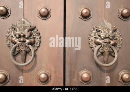 Close up de deux heurtoirs de porte en métal sur une porte en bois à l'intérieur de Tsz Shan monastery à Hong Kong, Chine Banque D'Images