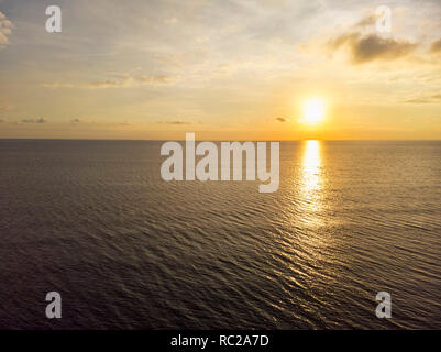 Heure d'or coucher de soleil sur l'océan avec des nuages et l'eau calme Banque D'Images