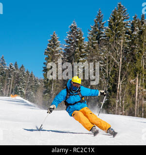 Male skier ski dans les montagnes à l'hiver. Ciel bleu et de la forêt d'hiver sur l'arrière-plan Banque D'Images