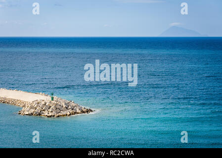 Port avec brise-lames et phare vert sur la mer turquoise de l'eau. Capo D'Orlando, en Sicile. Banque D'Images