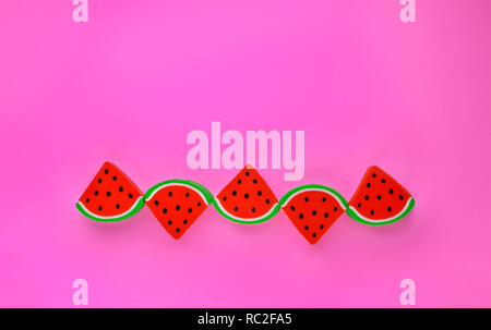 Un groupe de gommes en forme de tranches de melon dans une rangée sur un arrière-plan coloré ,composition simple Banque D'Images