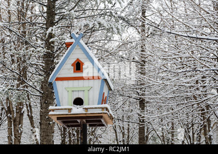 Wooden birdhouse accroché à l'extérieur en hiver, recouvert de neige Banque D'Images