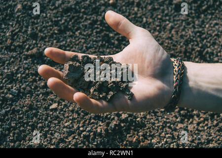 Close-up of a human hand holding certaines roches volcaniques Banque D'Images